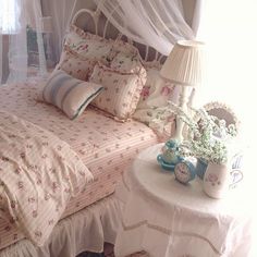 a bed with pink and white bedspread next to a table with flowers on it