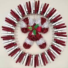 a red and white christmas wreath with a teddy bear in the middle surrounded by other decorations