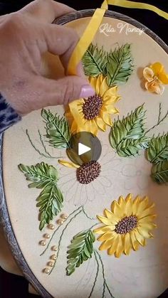 a person is painting sunflowers on a white plate with yellow ribbon and scissors