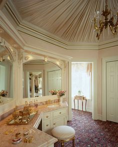 a fancy bathroom with chandelier, vanity and mirror on the ceiling is decorated in gold