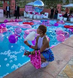 a woman sitting in front of a pool filled with balloons