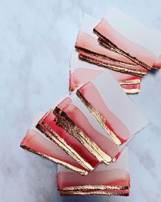 pink and gold desserts sitting on top of each other next to some white paper