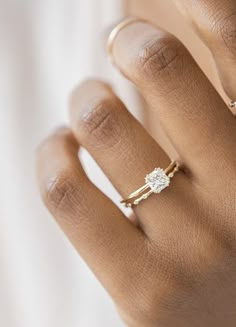 a woman's hand wearing a gold ring with a diamond in the middle and two diamonds on each band