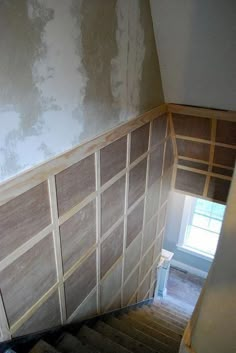 an empty room with wood paneling on the wall and stairs leading up to it