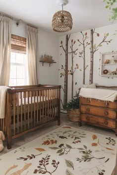 a baby's room with a crib, dresser and tree mural on the wall