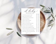 a printable baby shower checklist on a plate next to an olive branch and leaves