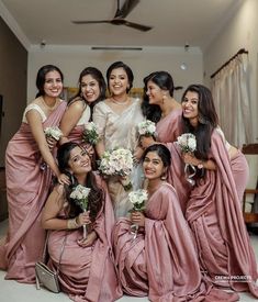 a group of women standing next to each other wearing pink dresses and holding bouquets