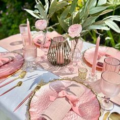 a table set with pink plates and silverware