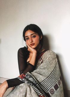 a woman sitting on the floor with her hand under her chin