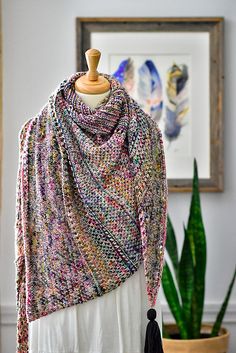 a knitted shawl draped over a white dress in front of a potted plant