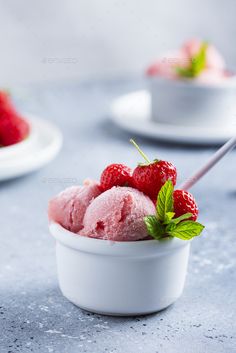 three scoops of ice cream in a bowl with raspberries