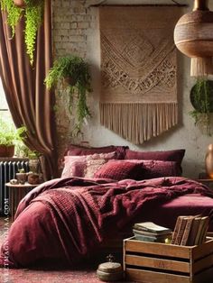 a bedroom with red bedding and hanging plants on the wall, along with wooden crates