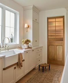 a kitchen with white cabinets and an area rug on the floor next to the sink