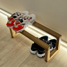 two pairs of shoes are sitting on a wooden bench next to a wall and floor