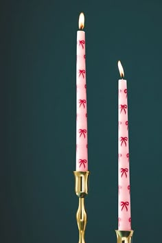 two candles with pink bows on them sitting next to each other