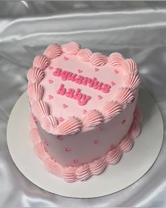 a heart shaped cake with pink frosting on a white plate