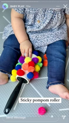 a baby playing with a ball and pom - pom roller on the floor