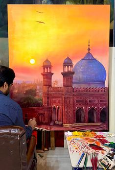 a man sitting in front of a painting with an orange sky behind him and buildings on the other side