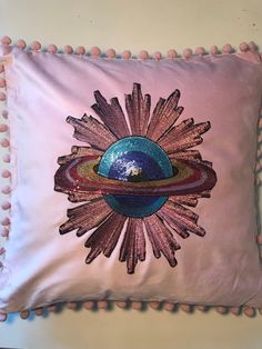 a pink pillow with an image of the sun on it and pom - poms