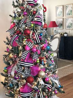 a decorated christmas tree in a living room with pink and green ornaments on the top