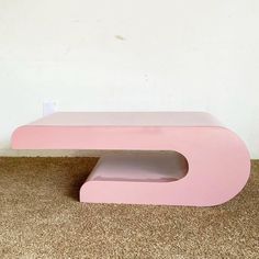 a pink table sitting on top of a carpeted floor next to a white wall