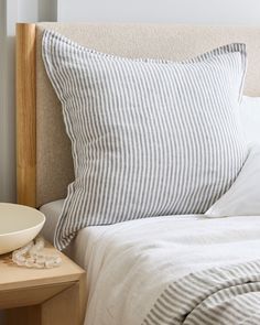 a bed with white and grey striped pillows