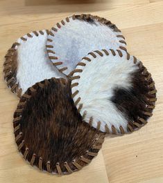 three brown and white animal hide coasters on a wooden table