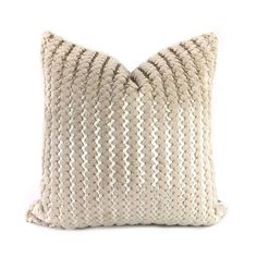 a white pillow with braiding on the front and back side, sitting on a white surface