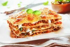 a stack of lasagna on a plate with sauce and parmesan cheese