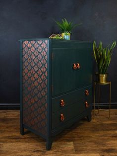 a green chest of drawers next to a potted plant on top of a wooden floor