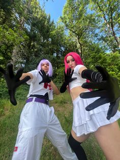 two women dressed in cosplay clothes standing next to each other on the grass