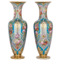 two large vases sitting next to each other on a white surface with flowers painted on them