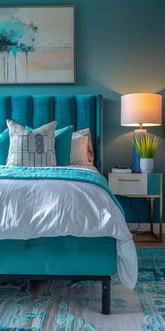 a bed with blue and white pillows in a bedroom next to a painting on the wall