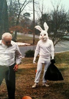 two men in bunny ears and white shirts are walking through the grass with an orange ball