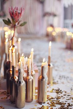 there are many bottles with candles in them on the table