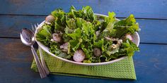 a bowl filled with lettuce and radishes on top of a green napkin