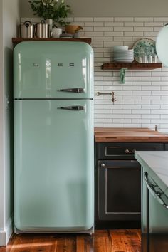 a mint green refrigerator in a kitchen with wood flooring and white brick backsplash