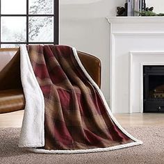 a living room with a couch, chair and fireplace covered in a red plaid blanket