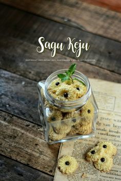 some cookies in a glass jar on top of an open book with the words saggu keju