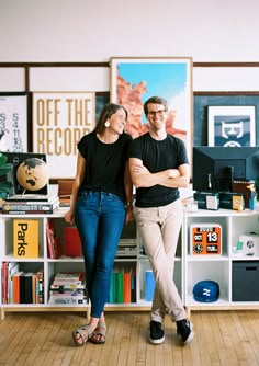 a man and woman standing next to each other in front of a book shelf filled with books