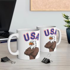 two coffee mugs with an eagle on them sitting next to a keyboard and mouse