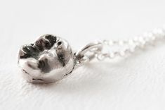 a silver cat's paw is hanging from a ball chain on a white surface