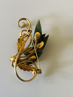 This vintage jade brooch has a leaf and flower like design done in 5 jade cabochons over a gold plated abstracted swirl and leaf metal form. The brooch is 2 inches wide and 1 inch tall. It has a gold tone metal base. It is backed with a 1 1/8 inch pin. I specialize in finding fun wearable jewelry. Please browse my shop for more options. I box jewelry sales in new gift boxes. Mid-century Yellow Gold Brooch For Gifts, Art Nouveau Gold Brooch With Cabochon, Gold Art Nouveau Brooch For Collectors, Unique Gold Brooch With Cabochon, Unique Gold Brooches With Cabochon, Mid-century Gold Brooch Jewelry, Jade Brooch, I Box, Wearable Jewelry