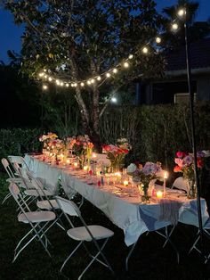 a long table is set up with candles and flowers for an outdoor dinner in the evening