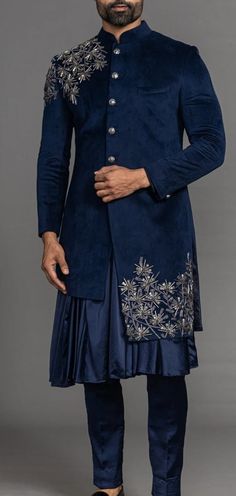 a man in a blue sherwa with gold embroidery on the chest and sleeves