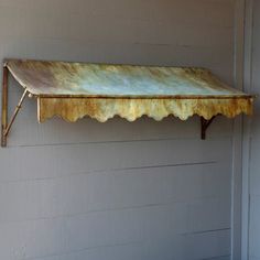 an old metal shelf hanging on the side of a building with scalloped edges