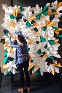 a woman standing in front of a giant sculpture made out of folded up pieces of paper