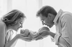 a man and woman holding a baby in their hands