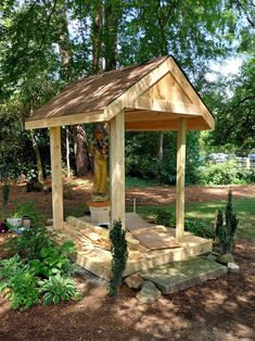 a wooden gazebo sitting in the middle of a park surrounded by trees and shrubs