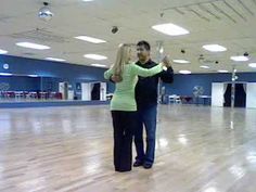 a man and woman are dancing in an empty dance floor with their arms around each other